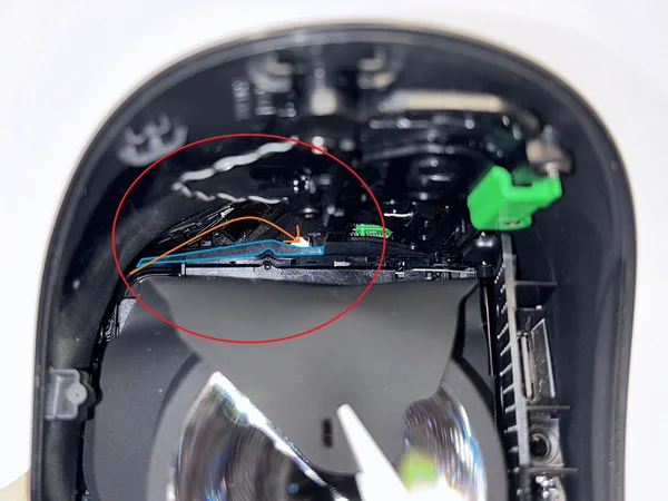 Pavyzdinis paveikslėlis su mėlynai pažymėta plastikine detalimi ir oranžine rodykle kabelio vedimui